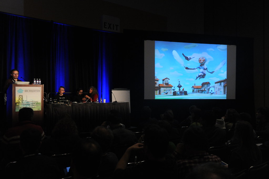 Speakers or panelists presenting at a Game Developers Conference session, viewed from the audience.