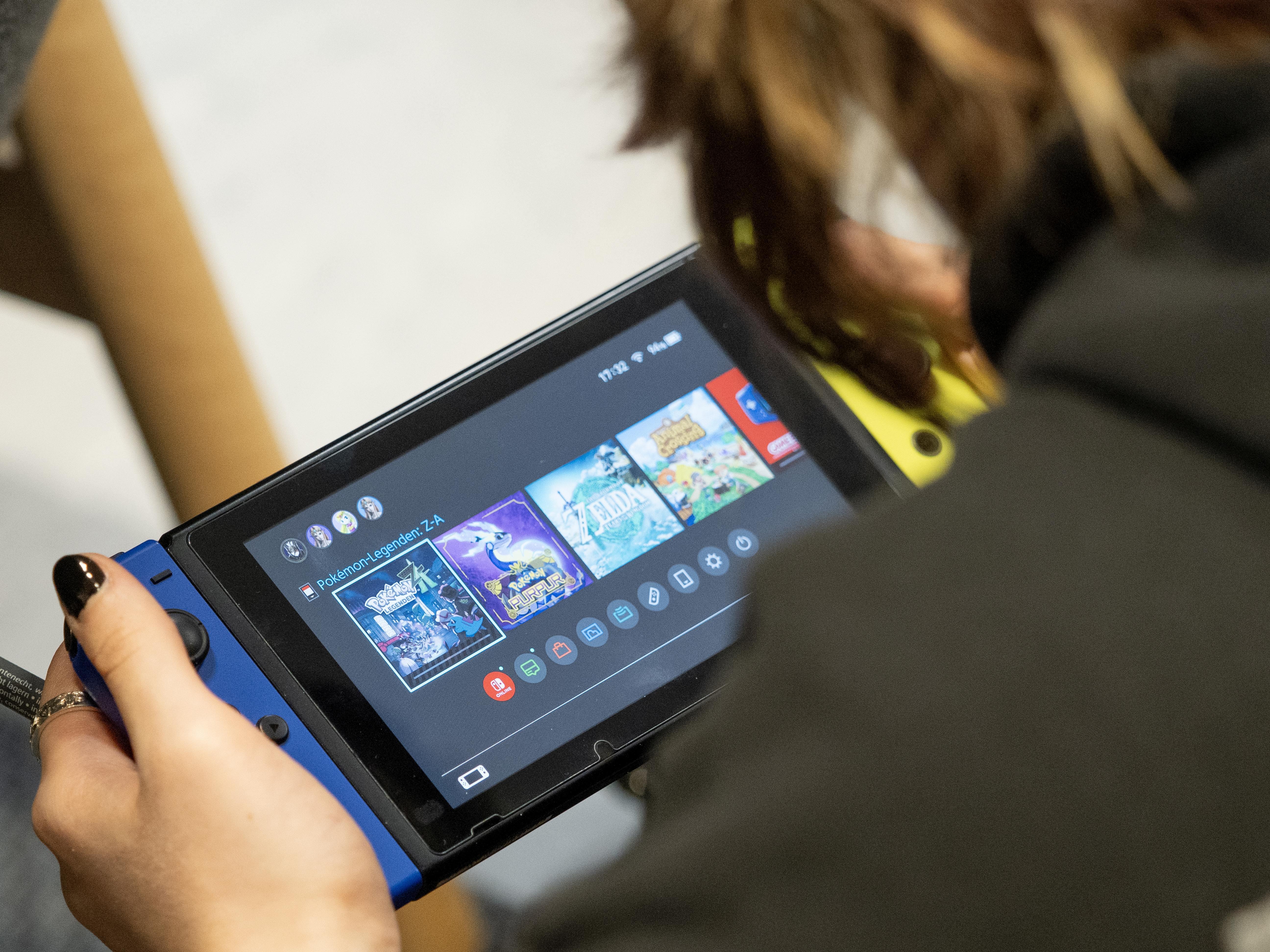 A person playing a Nintendo Switch handheld console, viewed from the side.